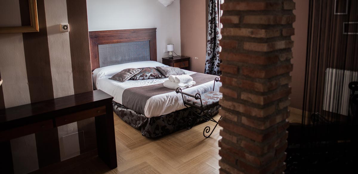 Fotografía donde se muestra una cama de matrimonio de una de las habitaciones del Complejo Rural Puerto Mágina.