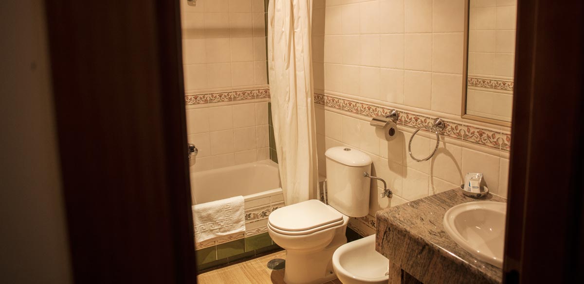 Vista de uno del os aseos de una habitación del Complejo Rural Puerto Mágina. Un inodoro, un bidé, un lavabo y una bañera.